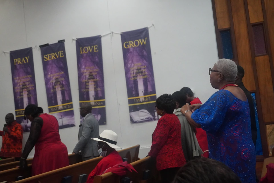 A congregant standing in prayer beneath the church banners