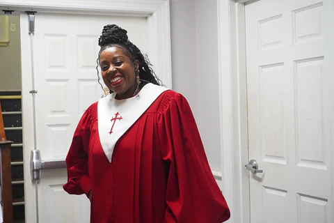 A robed choir member smiling in the church hallway